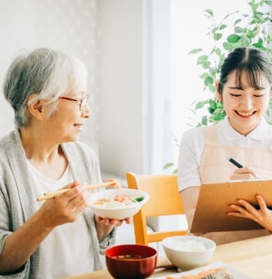 高齢者と職員が食事をしながらタブレットを見ている日常の交流風景